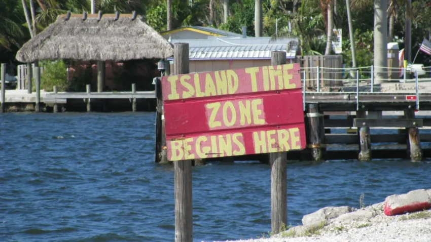 coastal sign that reads island time zone begins here.